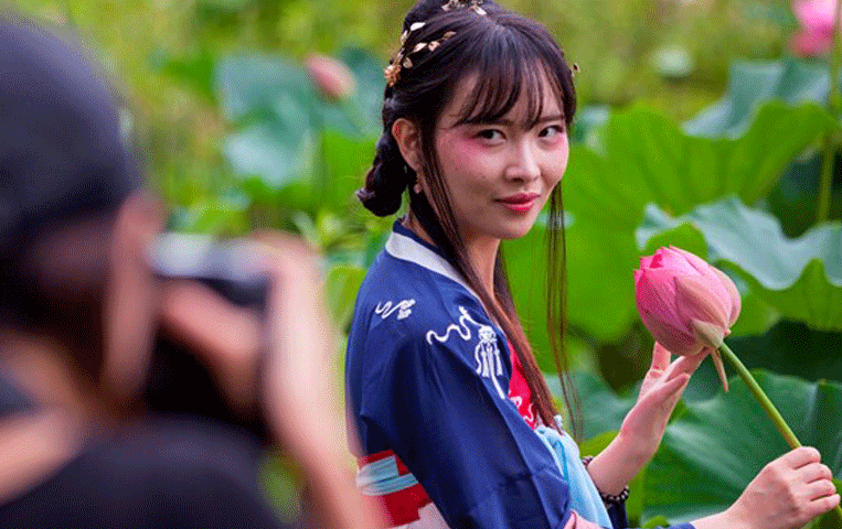 Photographer taking a picture of a woman in traditional Japanese attire holding a flower.